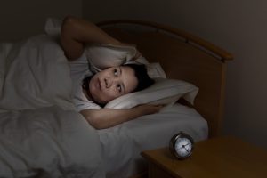 mature woman lying in bed struggling to sleep and looking up at the ceiling - insomnia